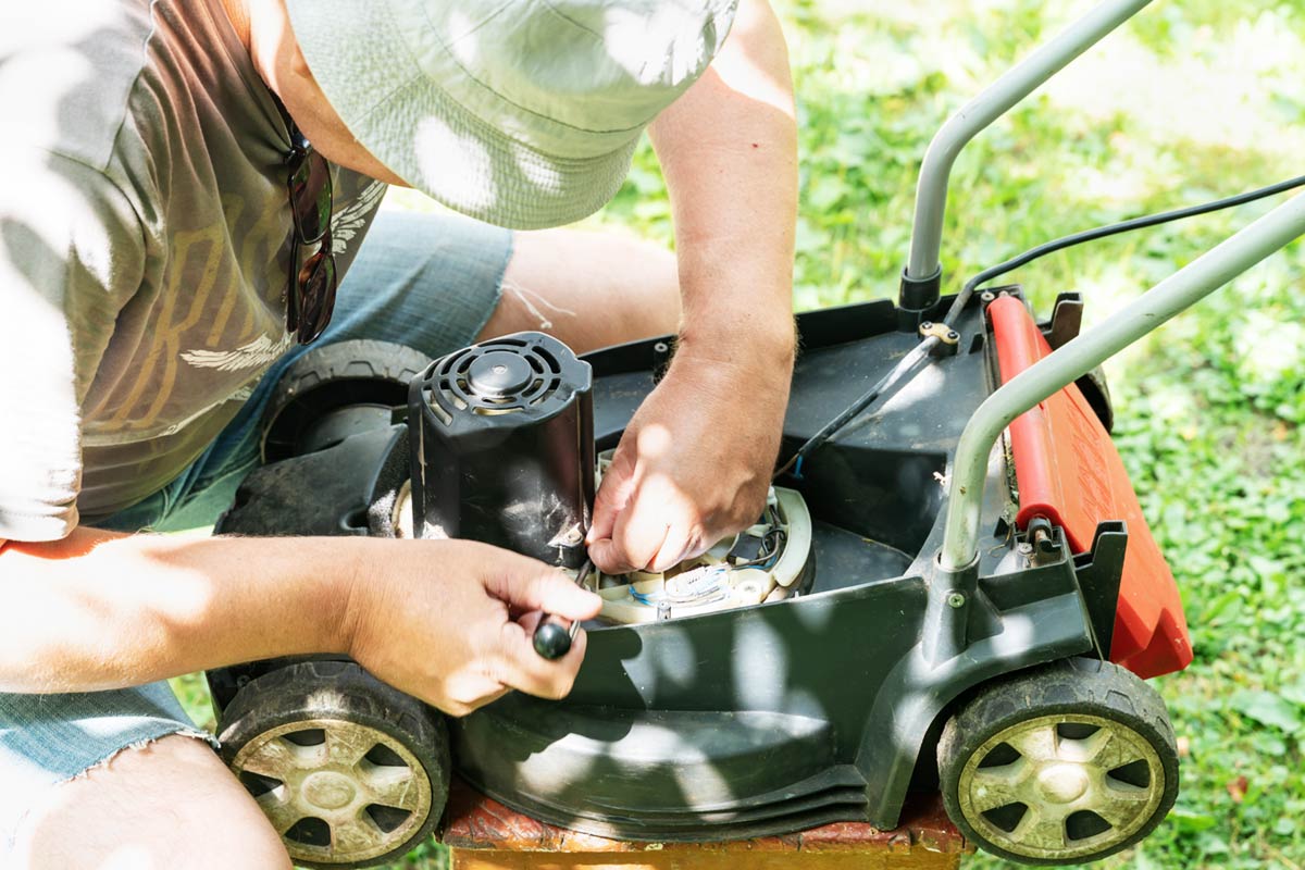 Jardinier répare sa tondeuse.